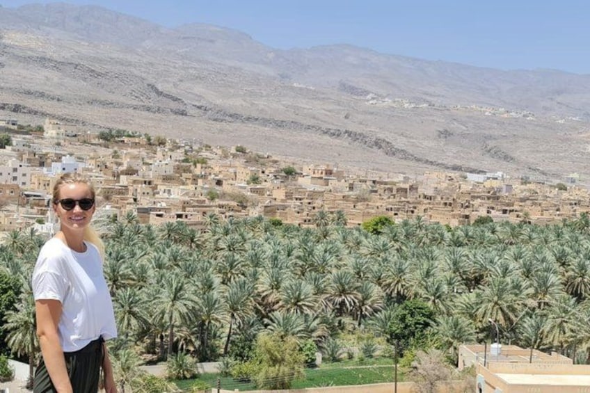 A person standing in front of a palm tree plantation with a mountainous backdrop. 2
