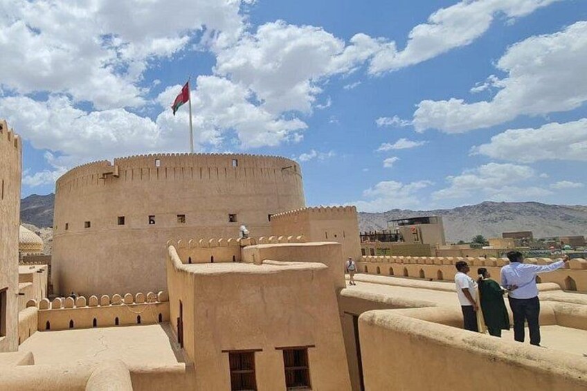 Un’antica fortezza con una bandiera, cielo sereno e montagne sullo sfondo. 2