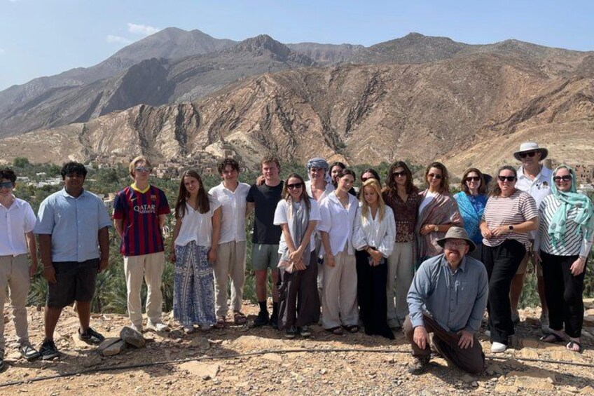 A group of people standing in a mountainous area with rocky terrain and sparse vegetation. 3