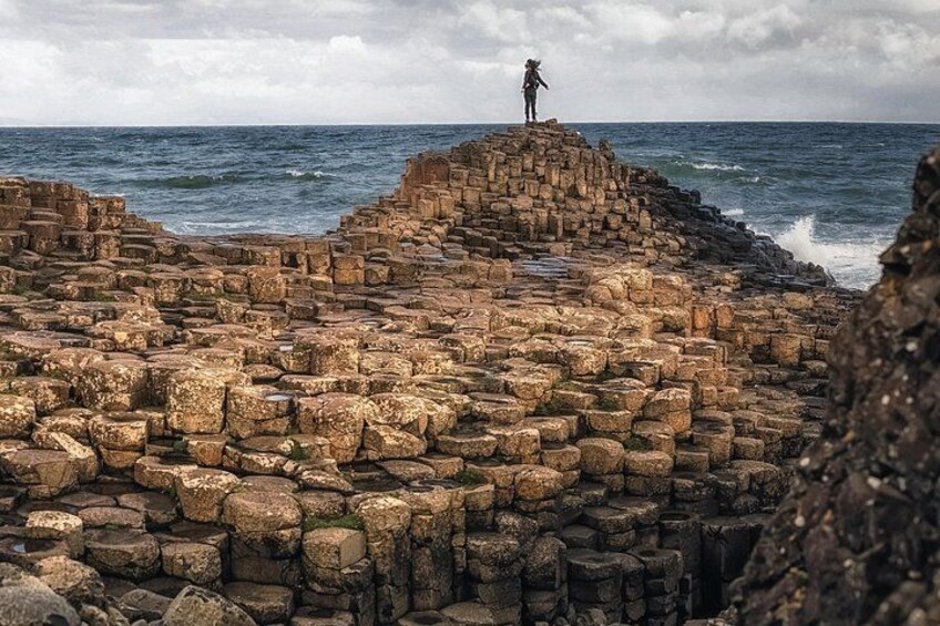 A rocky coastal structure with a person standing on top. 1
