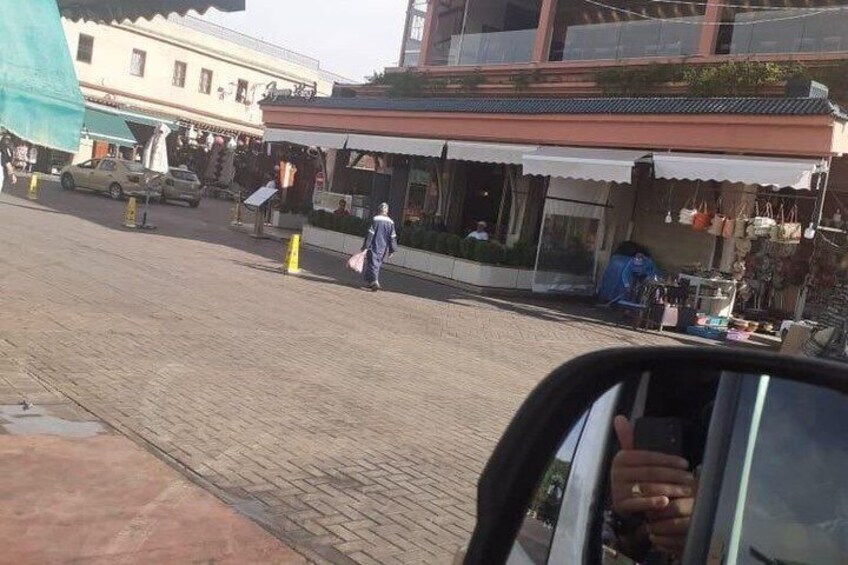 A street with shops, a person walking, and a car parked on the side. 5