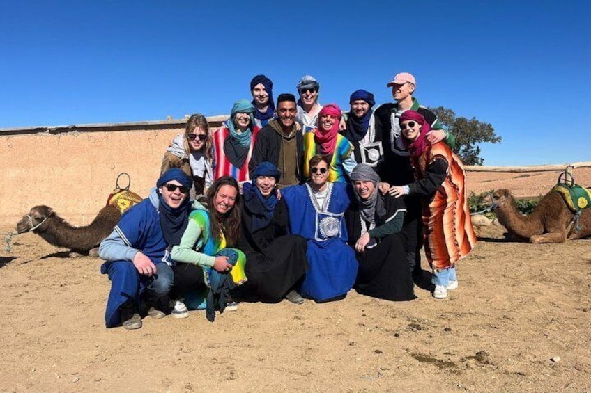 A group of people in a desert setting with camels. 1