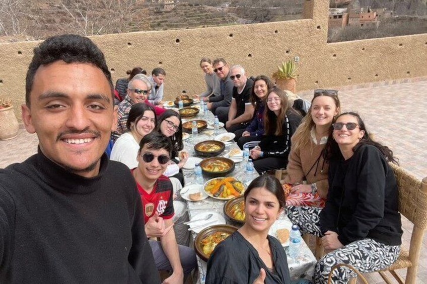 A group of people seated at a table outdoors with food and drinks. 4