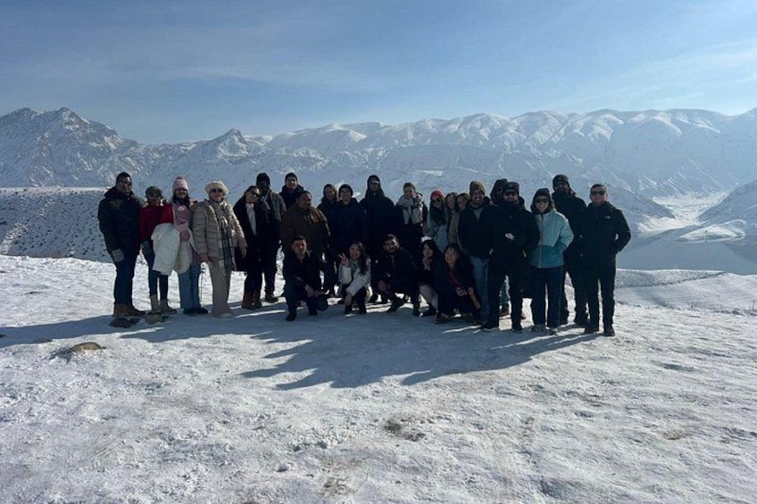 Un gruppo di persone in piedi su una montagna innevata, con cielo sereno e montagne sullo sfondo. 2