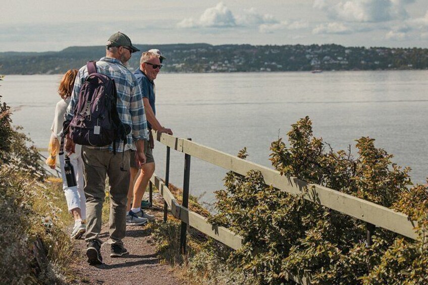 A group of people walking on a trail beside a body of water. 3