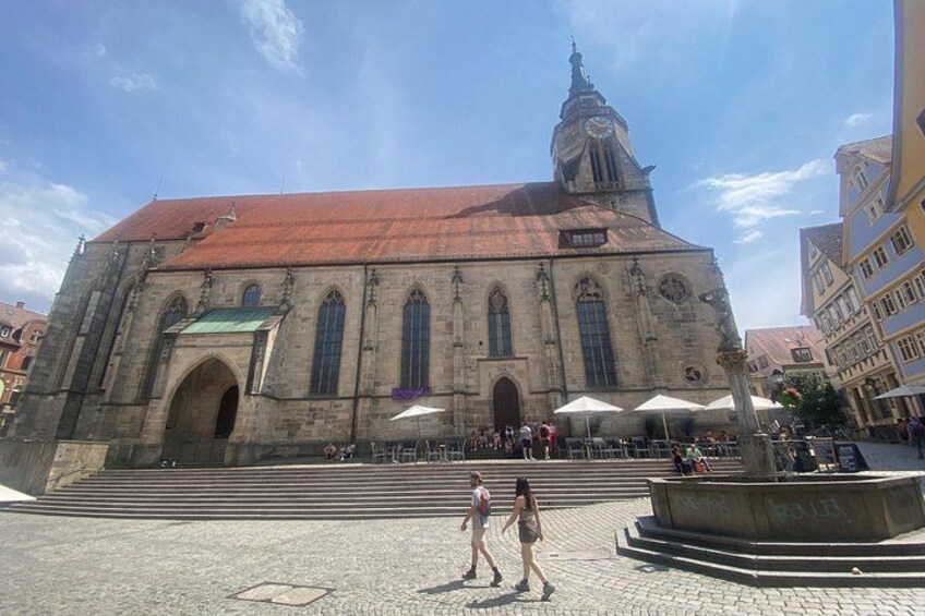 A historic church with a clock tower, steps leading up to the entrance, and a fountain in the foreground. 4