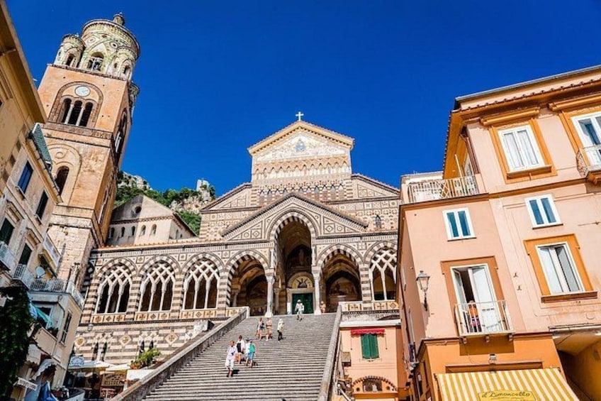 A historic church with a bell tower, arched windows, and a staircase leading to the entrance. 2