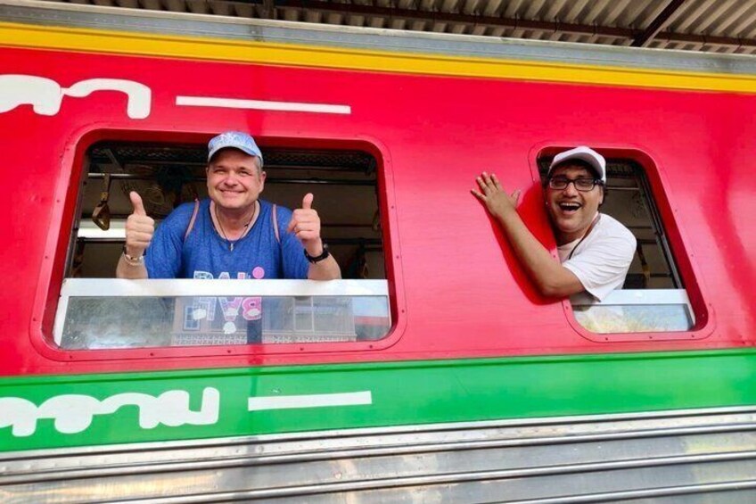 Two people giving thumbs up from a colorful train window. 2