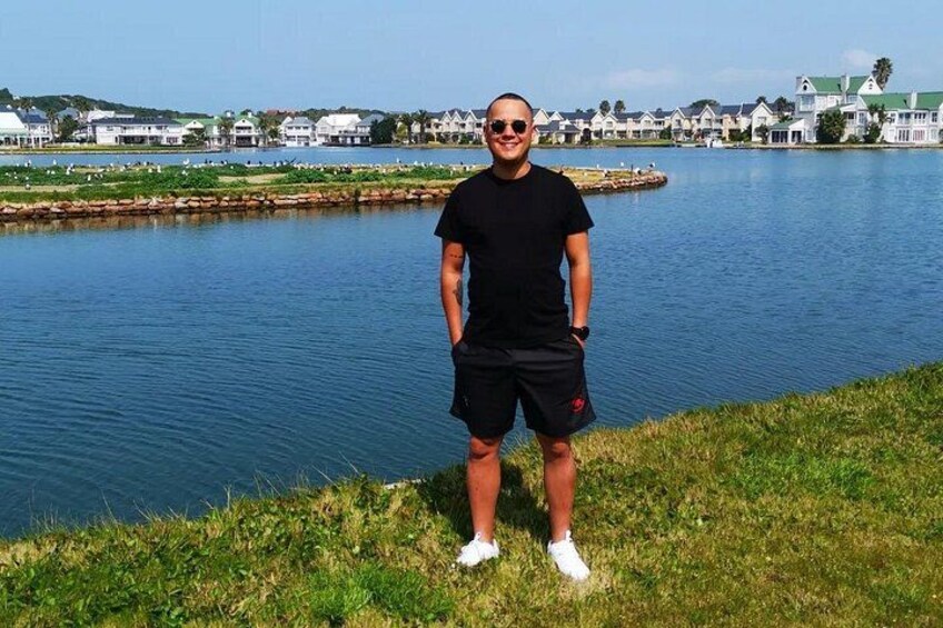 A person standing by a lake with houses in the background. 3