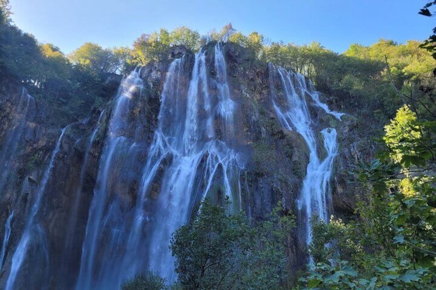 A waterfall cascading down a rocky cliff surrounded by dense foliage. 2