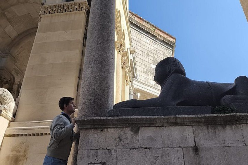 Une personne appuyée contre une colonne devant une statue de sphinx. 2