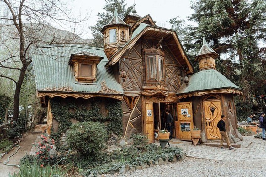 Una casa de madera con techo pronunciado y una torre, rodeada de follaje y árboles. 3