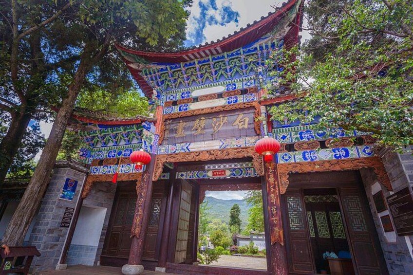 A traditional Chinese gate with intricate blue and red decorations, two red lanterns, and a sign with Chinese characters. 2