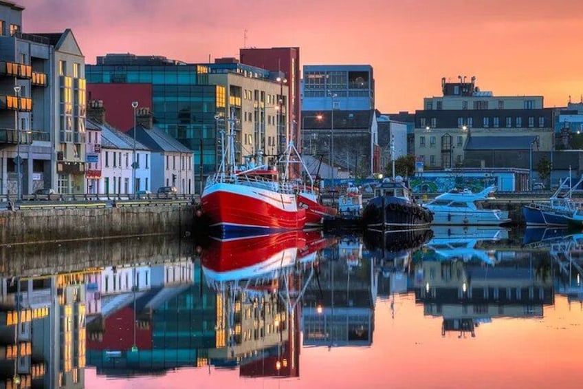 A harbor with boats, buildings, and a sunset reflection. 2