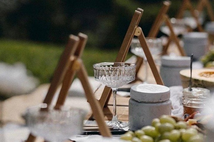 Un tavolo apparecchiato con bicchieri da vino, sottopiatti in legno e varie pietanze. 1