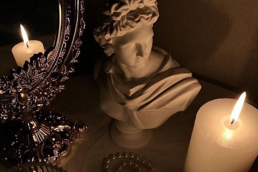 Un busto scolpito, uno specchio e due candele accese su un tavolo. 5
