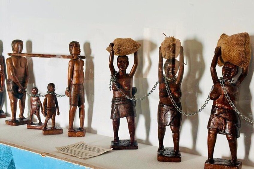 Wooden sculptures of figures with chains, some carrying objects. 4