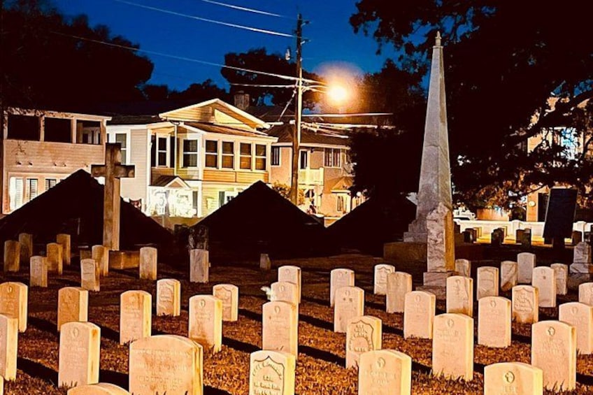 Un cementerio de noche con lápidas y un monumento. 2