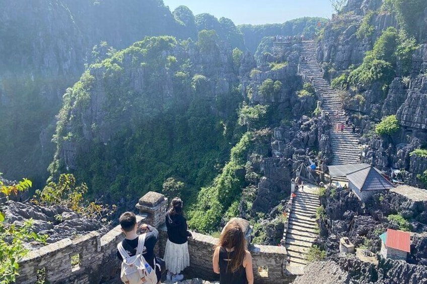 Eine steile Steintreppe, die durch üppiges Grün in bergiges Gelände hinaufführt. 4