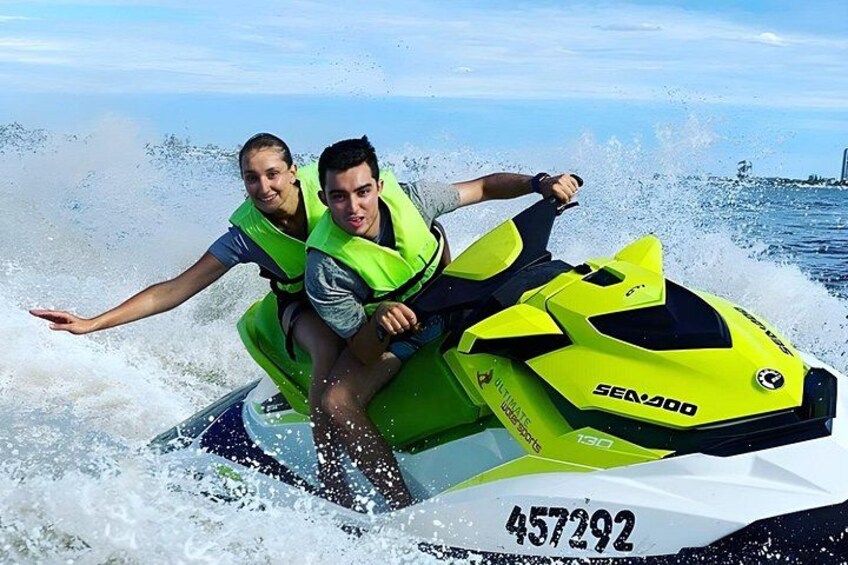Dos personas en un jet ski amarillo, con agua salpicando a su alrededor. 2