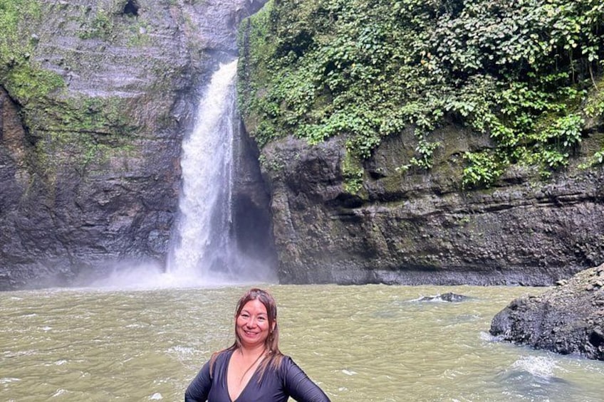 A waterfall, rocky cliffs, and a person standing in water. 3