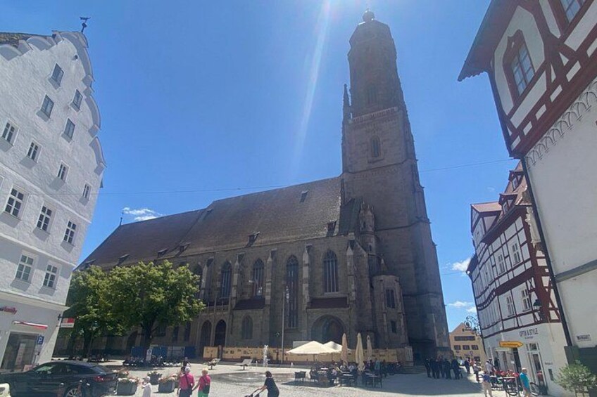 Una iglesia con una torre alta, rodeada de edificios tradicionales y un cielo despejado. 3