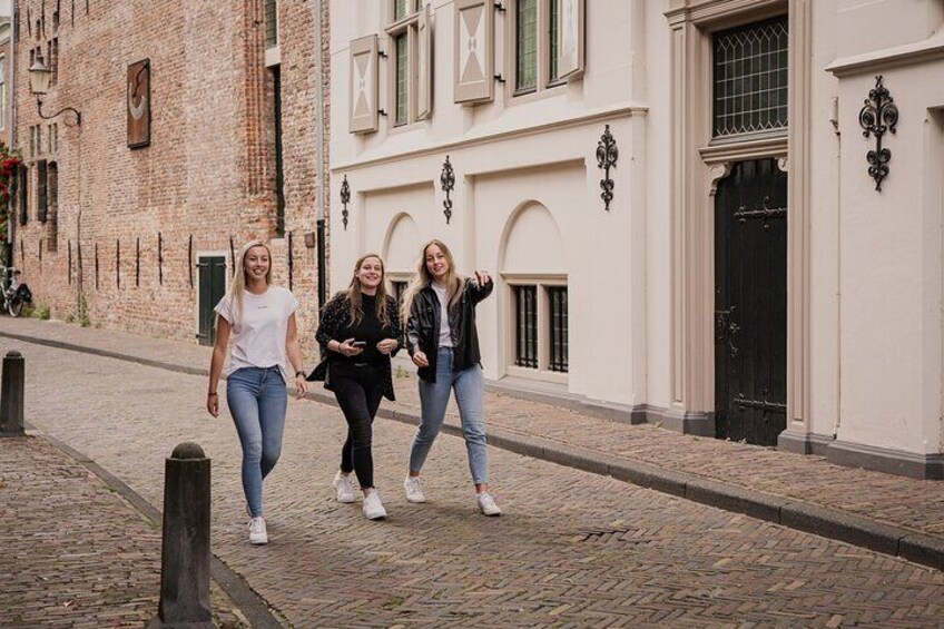 Three people walking on a cobblestone street in a historic town. 1