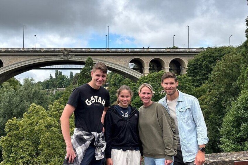 Four people standing in front of a bridge with greenery in the background. 2