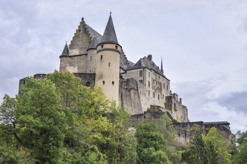 A historic castle with multiple towers and turrets, surrounded by lush greenery. 5