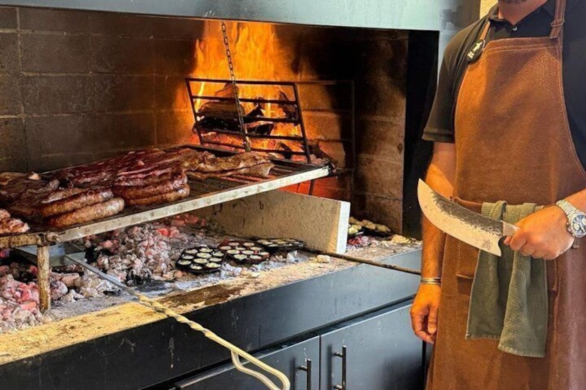 En person som grillar korv och annat kött över öppen eld. 2