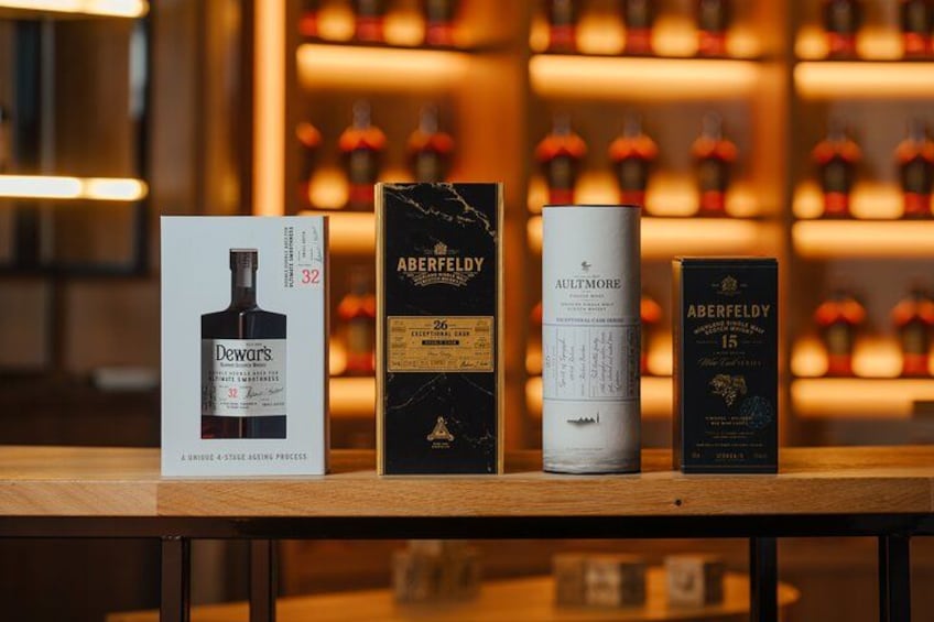 Three bottles of whiskey on a wooden table with their boxes. 1