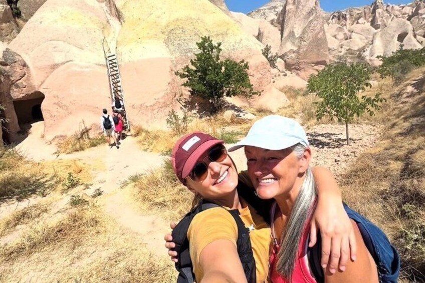 Two people taking a selfie with a rocky landscape and a ladder in the background. 4