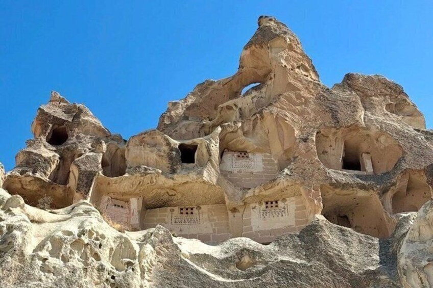 A rock formation with multiple caves and inscriptions. 5