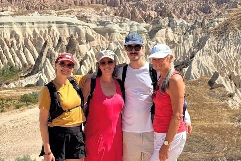 A group of four people standing in a desert landscape with distinctive rock formations. 1