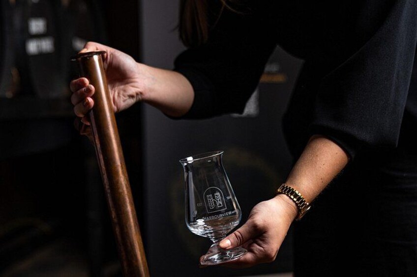 A person holding a copper shaker and a clear glass with a label. 5