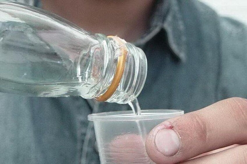 Een heldere glazen fles wordt in een transparante plastic beker gegoten. 4