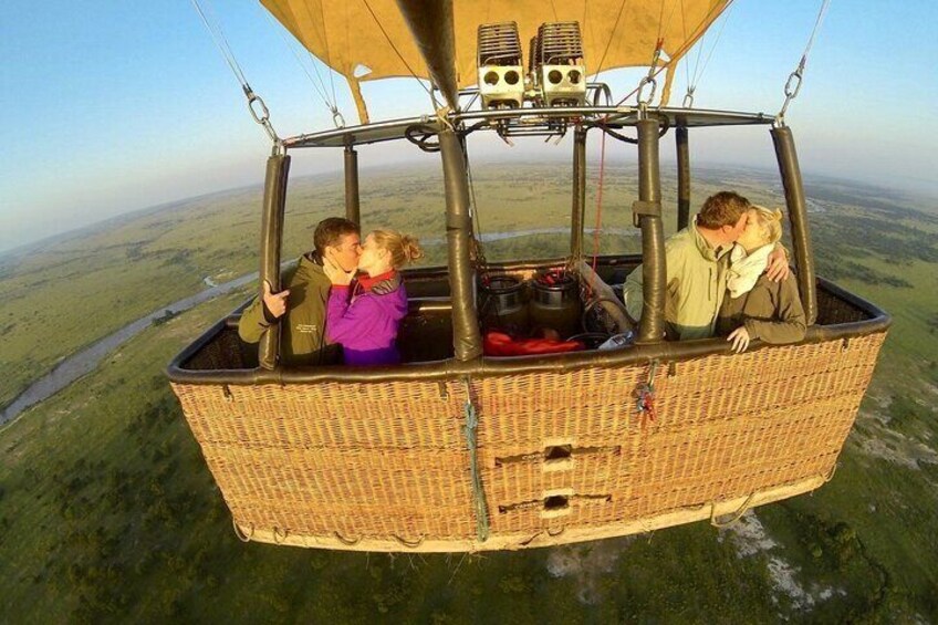 Un globo aerostático de mimbre con dos personas volando sobre un paisaje. 5