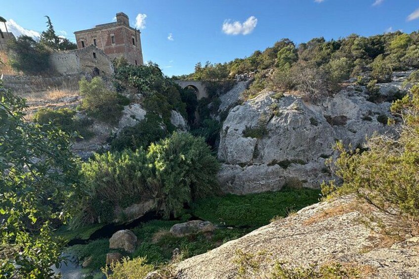 A rocky landscape with a small building and a bridge. 2