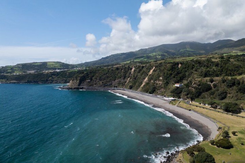 A coastal landscape with a beach, ocean, and rolling hills. 3