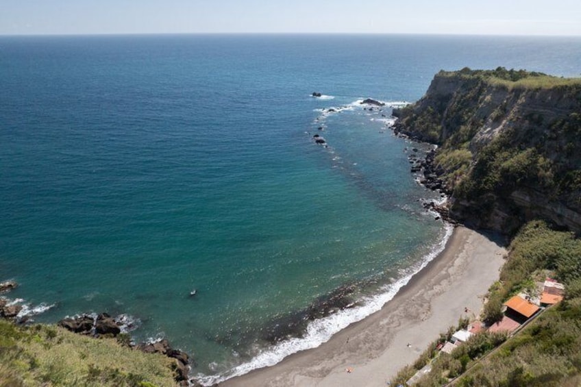 A coastal landscape with a beach, cliffs, and a clear view of the ocean. 4