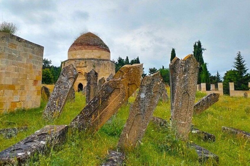 An ancient stone structure with a dome, surrounded by grass and trees. 2