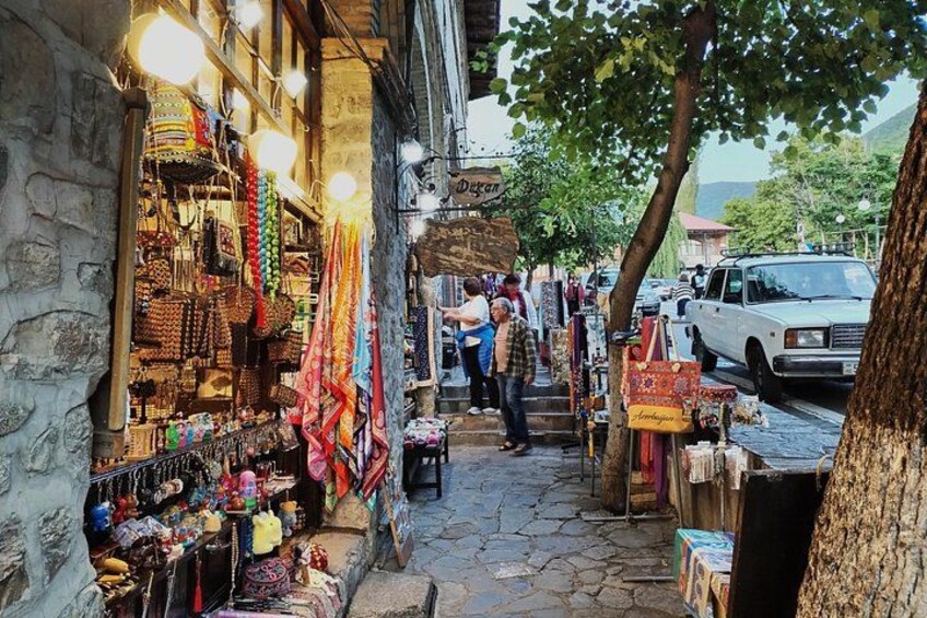 A narrow street with shops on one side and a parked car on the other. 5
