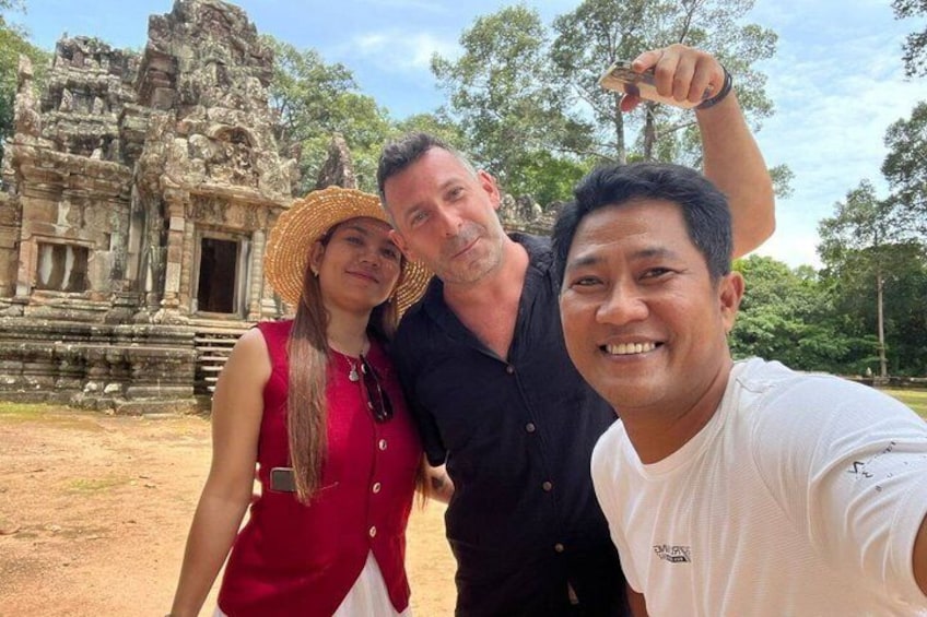 Three people posing in front of a temple with intricate carvings. 3