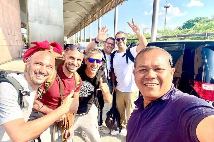 A group of people taking a selfie near a building with a covered walkway. 1