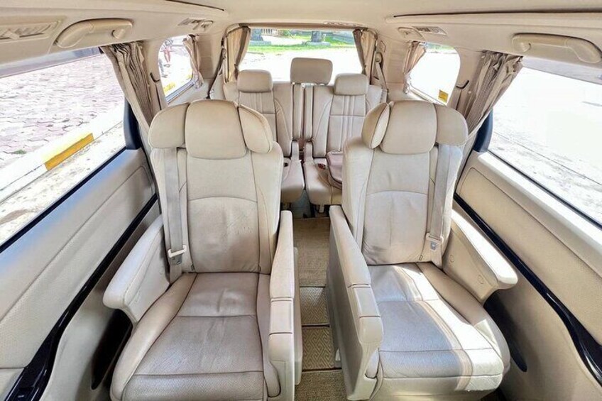 The interior of a vehicle with beige leather seats and a central aisle. 2