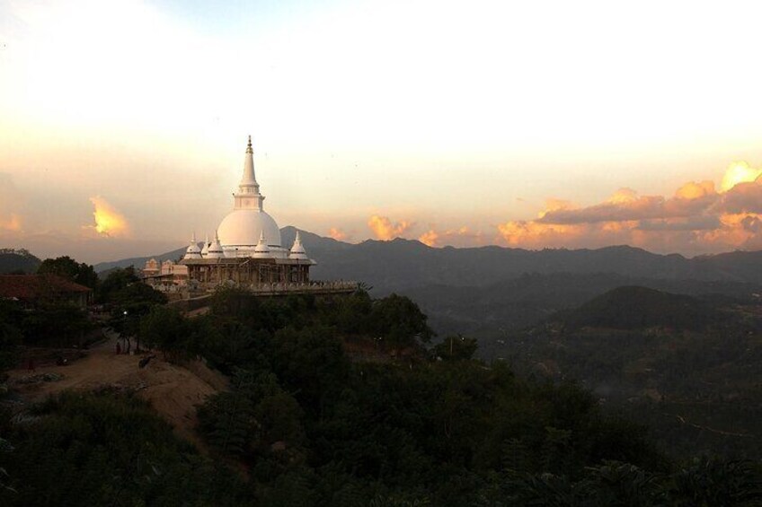 Eine weiße Stupa auf einem Hügel, mit einer Berglandschaft im Hintergrund. 2