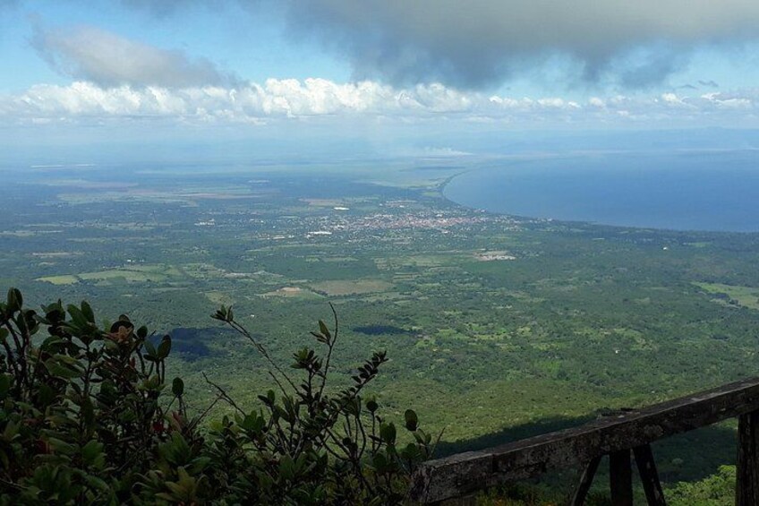 A coastal landscape with a view of the sea, a distant town, and a wooden fence. 3