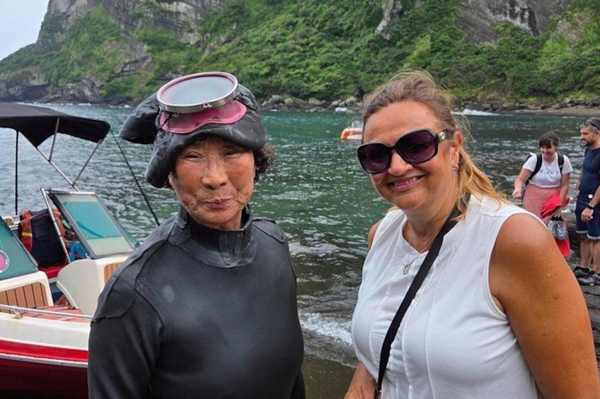 Two people near a boat on a body of water with a rocky coastline in the background. 4