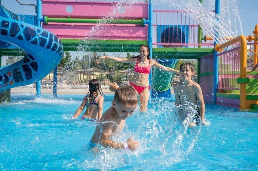 Children playing in a water park with a colorful slide and water features. 1