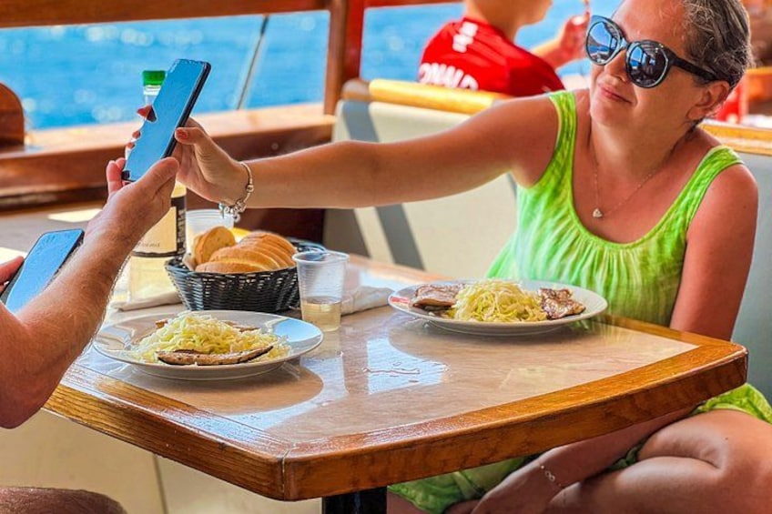 A person holding a smartphone, a plate with food, and a drink on a table. 3